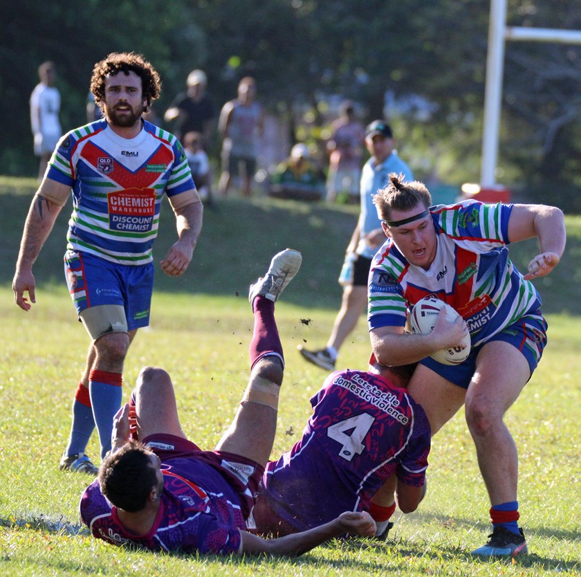 Innisfail's Jaymon Moore uses brunt strength to brush off one Yarrabah defender and tries to step out the tackle of another. Photo: Maria Girgenti