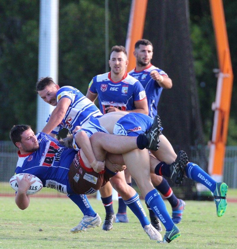 Atherton's James Coyle is dumped to the ground by two Cairns Brothers players. Photo: Maria Girgenti