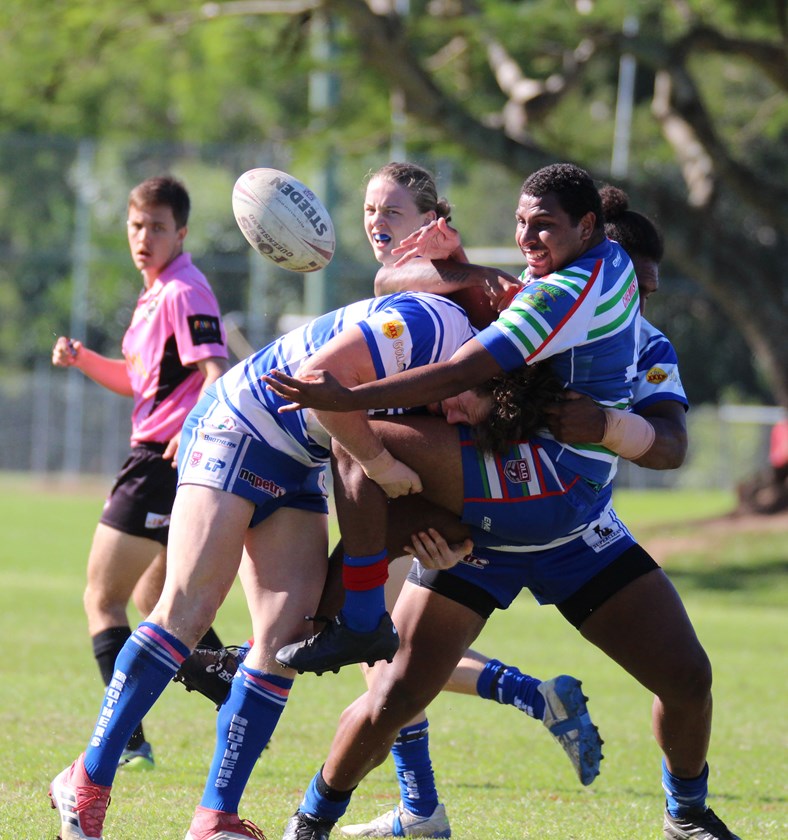 Innisfail's Elia Mooka manages to offload the ball despite being wrapped up by two Cairns Brothers players Photo: Maria Girgenti 