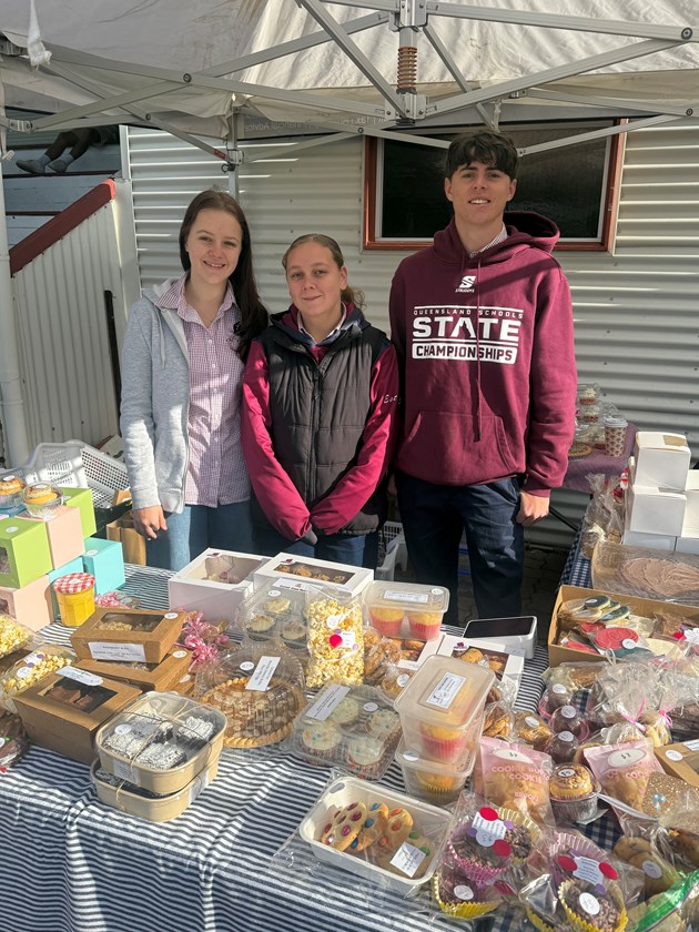 Dalby Devils Samara Mittelstadt (left), club captains Mia Deem and Cooper Collins man the bake sale to raise money for McGrath Foundation breast cancer nurses in Dalby.